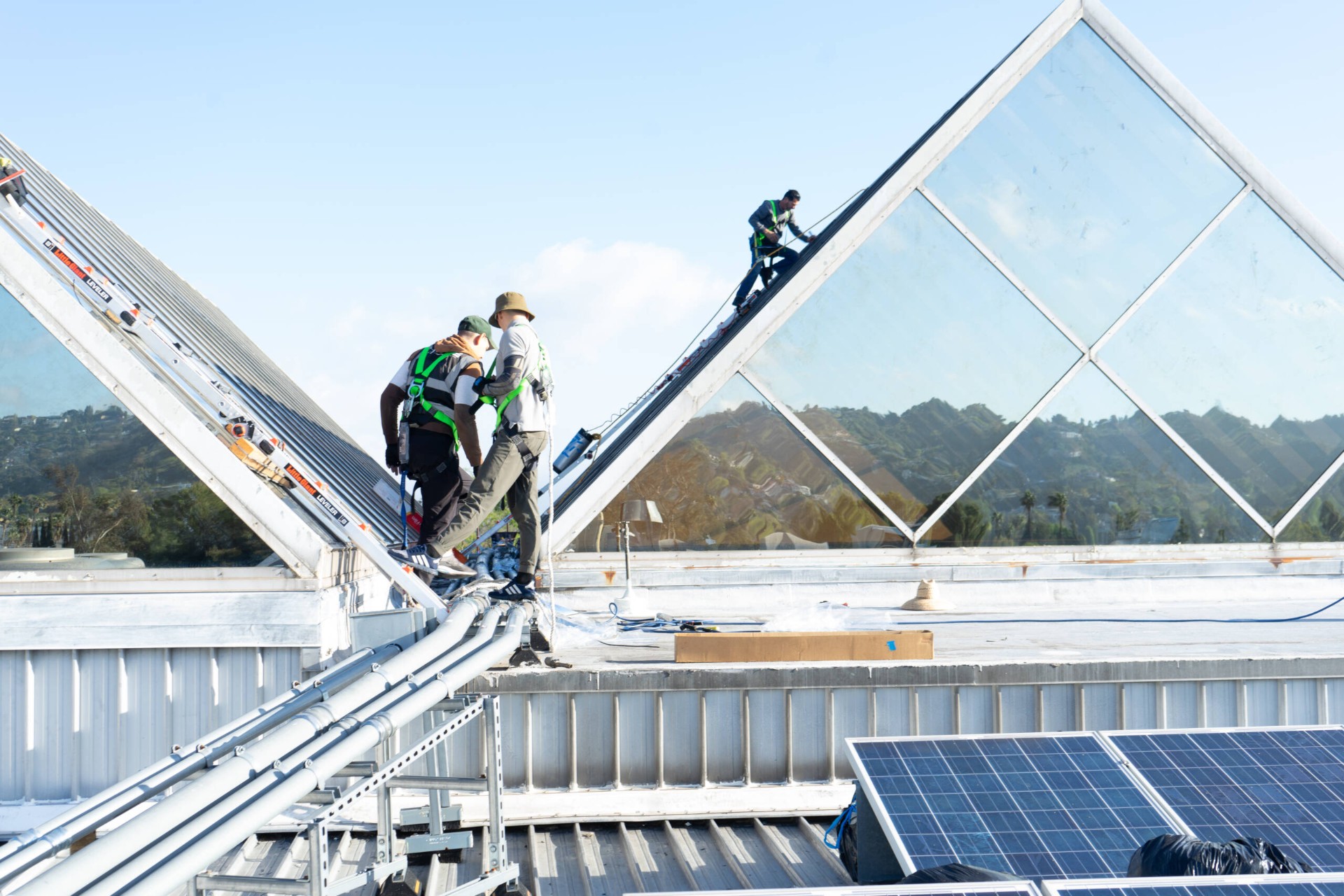 Professional team installing window film on large commercial skylights with safety harnesses